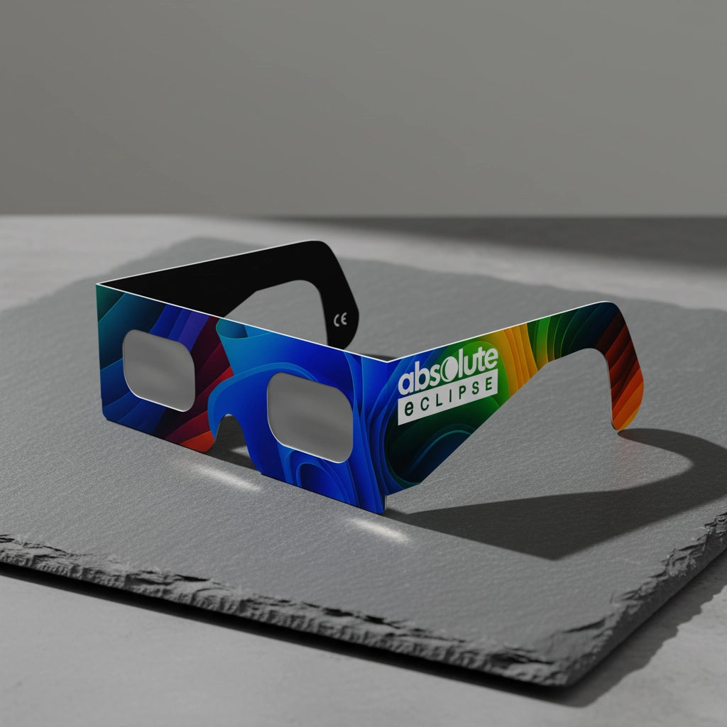 A Breeze design solar eclipse glasses resting on a polished slate slab, illuminated by soft morning light. CE certified for safe viewing.