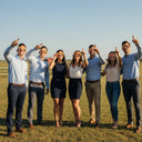 Un grupo diverso de compañeros con gafas diseño Bull, mirando al cielo con asombro durante un evento de team-building en un rancho soleado.