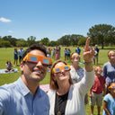 Familias y compañeros reunidos en un evento comunitario, todos con gafas diseño Bull, compartiendo la emoción por el eclipse del 12 de agosto de 2026.