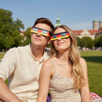 A young German couple enjoying a sunny day in Munich, wearing DE glasses, looking up in awe for the August 12, 2026 eclipse.