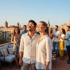 Group of friends celebrating on a rooftop in Barcelona, wearing ES glasses and sharing joyful moments under a bright sky.
