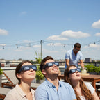 A group of friends on a rooftop wearing EVA glasses, looking up at the sky, capturing the joy of a sunny day.