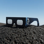 EVA solar eclipse glasses on a textured volcanic rock surface under bright sunlight, showcasing sleek design.