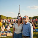 Reunión comunitaria en un parque de París, multitud diversa con gafas para eclipse solar FR, celebrando juntos el 12 de agosto de 2026.