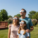 Family wearing goldline eclipse glasses in their backyard, sharing a moment of wonder under the bright sky.