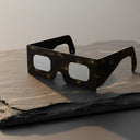 Elegant gold line design solar eclipse glasses on a dark slate slab, CE certified for safe viewing.