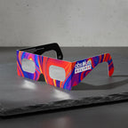 Showcasing Goo design solar eclipse glasses at an angle on a textured slate stone. ISO 12312-2 certified for safe viewing.