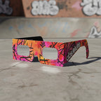 Graffiti design solar eclipse glasses resting on a gritty concrete surface, perfect for safe viewing. ISO 12312-2 certified.