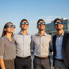 Young professionals on a corporate rooftop wearing helmet-design glasses, gazing skyward in a warm afternoon light.