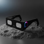 Professional product photograph of helmet-design eclipse glasses on lunar-like rock, ISO 12312-2 certified.