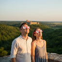 Una pareja mirando al cielo con gafas para eclipse solar, compartiendo juntos un momento de asombro. Certificadas CE.