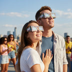 A happy young couple wearing neon eclipse glasses on a sun-drenched rooftop, gazing up at the bright sky together.
