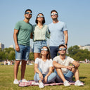 Four friends enjoying a sunny park, all wearing solar eclipse glasses and looking up at the bright sky. CE certified.