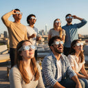 A vibrant rooftop party scene with friends wearing reflective glasses, all gazing up at the sky during a sunny afternoon.