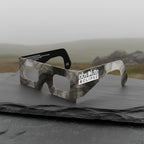 A professional showcase of Soot design eclipse glasses on a textured slate slab, perfect for safe viewing. ISO 12312-2 certified.