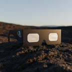 Elegant showcase of Stranded design solar eclipse glasses on textured volcanic rock, perfect for safe viewing. CE certified.