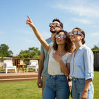 Three friends at a backyard party wearing Sunburst eclipse glasses, gazing up at the sky. Ideal for safe viewing on August 12, 2026.